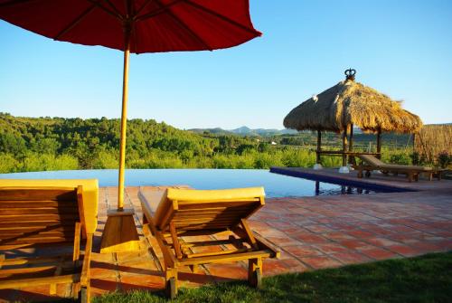 two chairs and an umbrella next to a pool at Masía Durbá Hotel in Castellnovo