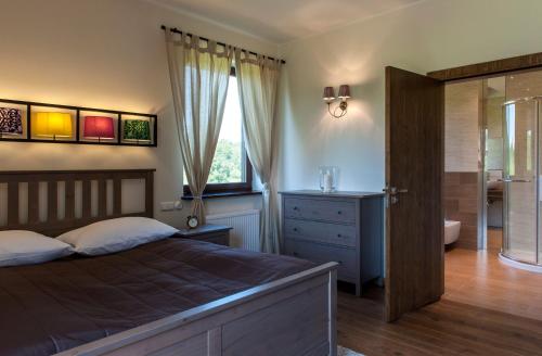 a bedroom with a bed and a bathroom at Hotel SPA Dr Irena Eris Wzgórza Dylewskie - Siedliska in Wysoka Wieś