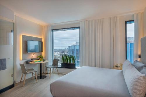 a hotel room with a bed, chair, table and window at INNSiDE by Meliá Amsterdam in Amsterdam