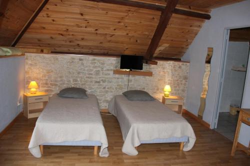 Duas camas num quarto com tectos e pisos em madeira em chevrerie de la huberdiere em Liesville-sur-Douve