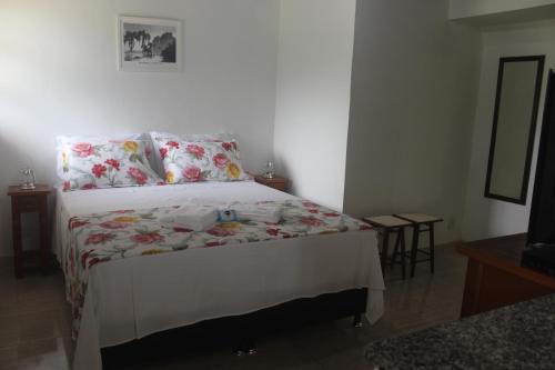 a bedroom with a bed with a floral bedspread at Luxor Flat`s in Miguel Pereira