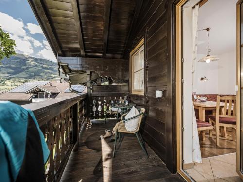 a room with a balcony with a chair and a table at Kinderbauernhof Scharrerhof in Hollersbach im Pinzgau