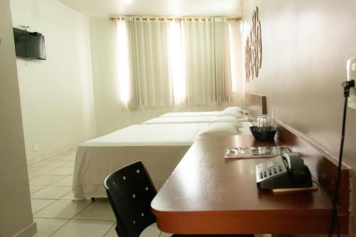 a room with two beds and a phone on a table at Contagem Centro Hotel in Contagem