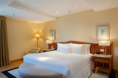 a hotel room with a large white bed and a chair at Windsor Barra Hotel in Rio de Janeiro