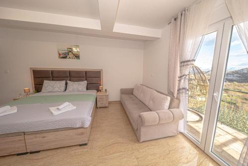 um quarto com uma cama, um sofá e uma janela em Skadar lake Apartments Pajovic em Virpazar