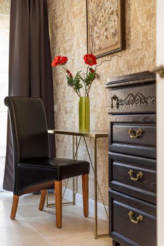 a desk with a chair and a vase with red flowers at Sakura_INN Palanga in Palanga