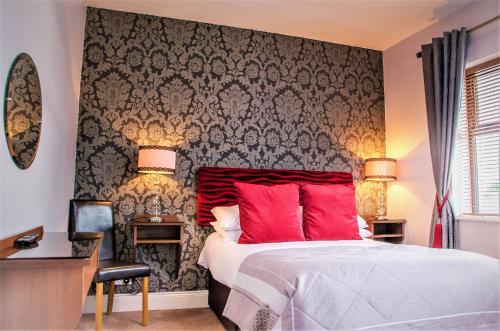 a bedroom with a bed with red pillows and a wall at Killaran House in Killarney