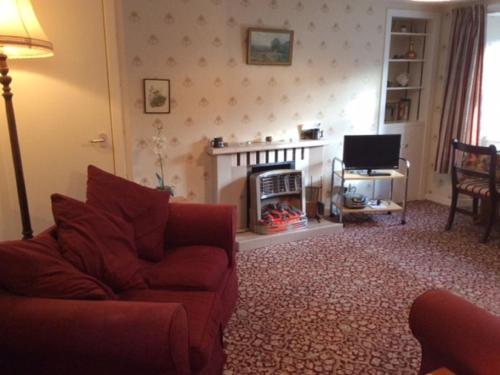 a living room with a red couch and a fireplace at Holiday Home Craigton Cottage by Interhome in Dunkeld