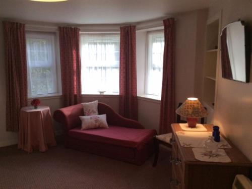 a living room with a couch and a chair and windows at Holiday Home Craigton Cottage by Interhome in Dunkeld