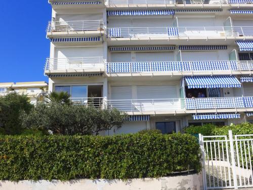 - un bâtiment blanc avec des balcons bleus et des personnes sur le balcon dans l'établissement Apartment Le Cormoran by Interhome, à Saint-Laurent-du-Var