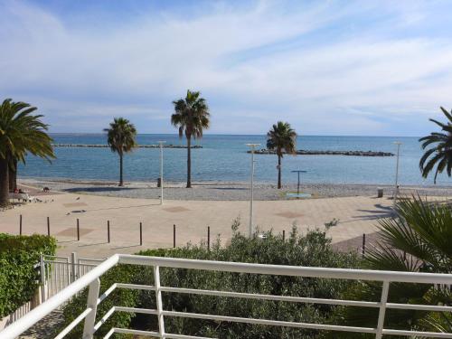 a beach with palm trees and the ocean at Apartment Le Cormoran by Interhome in Saint-Laurent-du-Var
