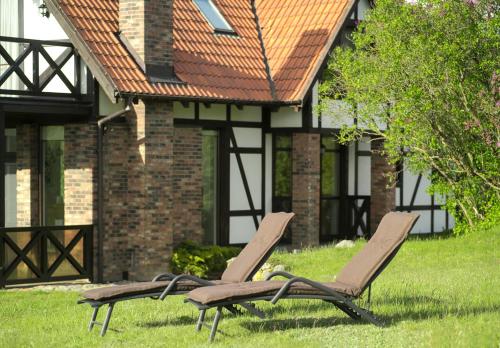 two chairs sitting in the grass in front of a house at Hotel SPA Dr Irena Eris Wzgórza Dylewskie - Siedliska in Wysoka Wieś