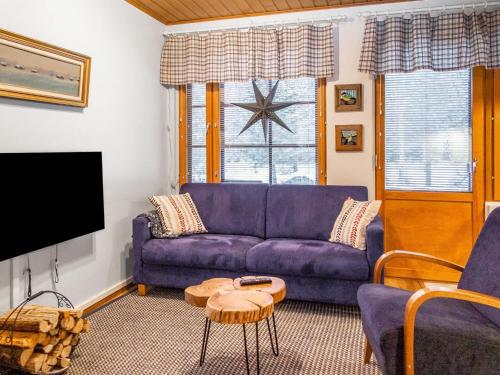 a living room with a purple couch and a tv at Holiday Home Alppitalo sinitähti 9 apt 2 by Interhome in Tahkovuori