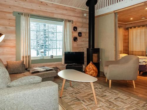 a living room with a couch and a table and a fireplace at Holiday Home Keselmäkangas by Interhome in Tikkala