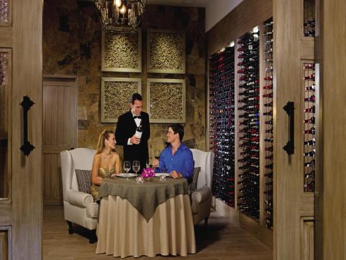 a group of people sitting at a table in a wine cellar at Secrets Puerto Los Cabos Golf & Spa18+ in San José del Cabo