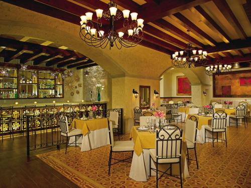 a restaurant with white tables and chairs and a chandelier at Secrets Puerto Los Cabos Golf & Spa18+ in San José del Cabo