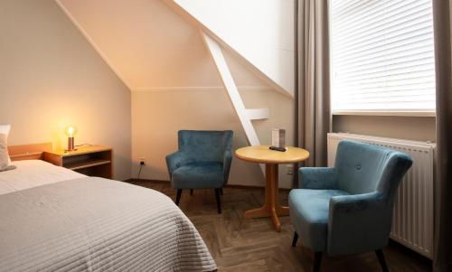 a bedroom with two chairs and a table and a bed at Hotel Restaurant Mondriaan in Winterswijk
