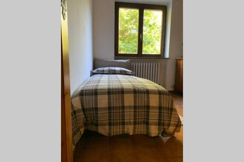 a bed with a plaid blanket in a room with a window at TRADITIONAL VILLA BELLAGIO san primo LAKE COMO in Bellagio