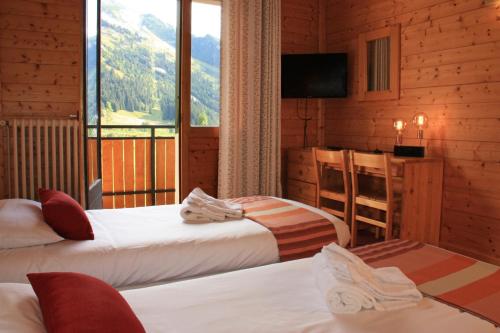 a hotel room with two beds and a window at Azureva La Clusaz les Confins in La Clusaz