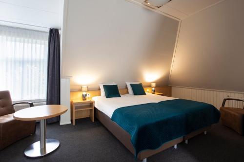 a hotel room with a bed and a chair and a table at Hotel Restaurant Mondriaan in Winterswijk