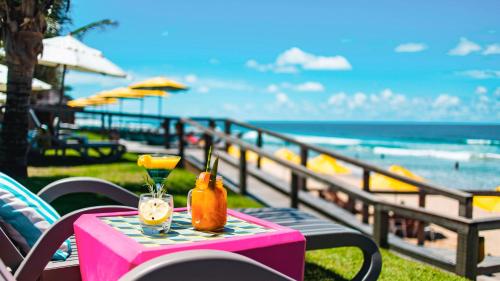 a table with two drinks on it with the beach at Kembali Hotel Porto de Galinhas - Adults Only in Porto De Galinhas