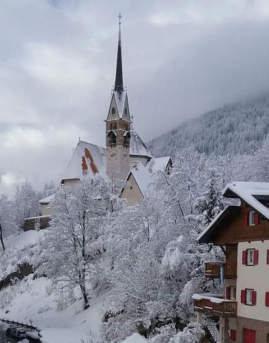 a church with a steeple in the snow at Ciasa Goti in Moena