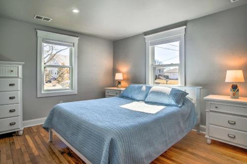 a bedroom with a blue bed and two windows at Updated Buzzards Bay Beach Cottage Walk to Shore! in Buzzards Bay