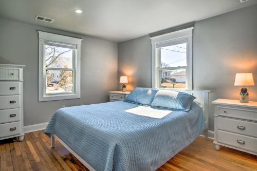 a bedroom with a blue bed and two windows at Walk to Shore: Updated Buzzards Bay Cottage! in Buzzards Bay