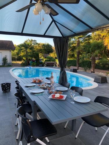 een blauwe tafel met eten naast een zwembad bij Villa Bergerac avec Piscine in Bergerac
