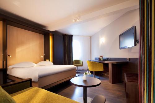 ヴァンヌにあるエスカル オセアニア ヴァンヌ サントルのベッドとデスクが備わるホテルルームです。