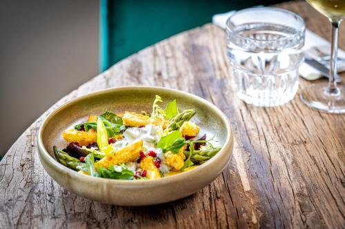 a bowl of salad on a wooden table with a glass of wine at Broeck Oudewater in Oudewater