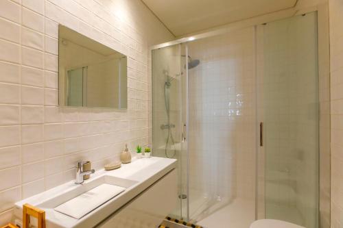 a bathroom with a sink and a glass shower at Oliveira Apartment`s in Porto