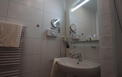 ein weißes Badezimmer mit einem Waschbecken und einem Spiegel in der Unterkunft Beurener Hof in Beuren