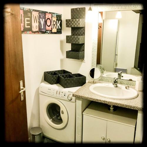 une salle de bain avec une machine à laver et un lavabo dans l'établissement Résidence des lentilles, à Schiltigheim