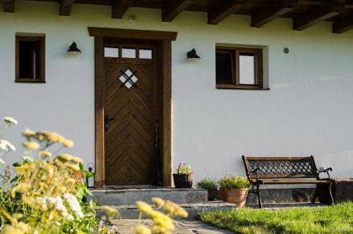 a house with a wooden door and a bench at Penzion V Poli in Klimkovice