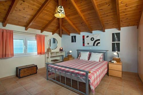 sypialnia z łóżkiem i drewnianym sufitem w obiekcie Maistro Beach House w Acharavi