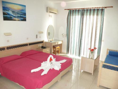 een slaapkamer met een groot rood bed met een witte bloem erop bij White Palace Pavlos apartment1 in Faliraki