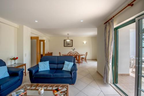 a living room with a blue couch and a table at Flor da Falésia Villas in Albufeira