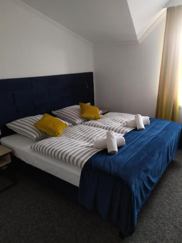 Bett mit gelber und blauer Bettwäsche und gelben Kissen in der Unterkunft Dom Przyjęć Pradziad in Rogów