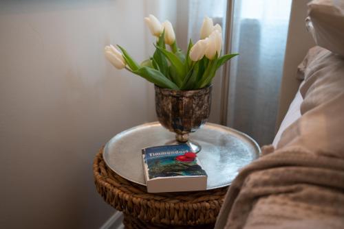 una mesa con un jarrón y un libro y flores en Studio-Apartment Piccolino 26, en Timmendorfer Strand