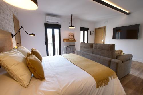 een slaapkamer met een groot bed en een bank bij Cuencaloft Apartamentos el Nazareno in Cuenca