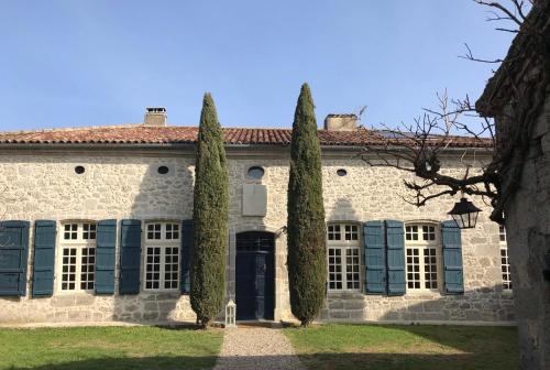 ein altes Steinhaus mit blauen Fensterläden und Bäumen in der Unterkunft Coeur de Calignac in Calignac