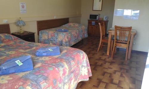 a hotel room with two beds and a table and chairs at Goolgowi Highway Motel in Goolgowi