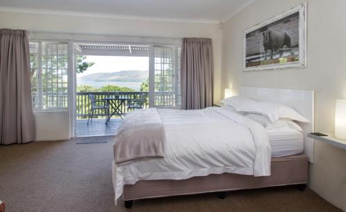 a bedroom with a large bed and a balcony at South Villa Guesthouse&Garden in Knysna