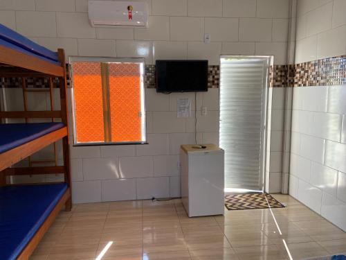 a dorm room with a refrigerator and a window at Guarajuba sitiofelizcidade in Guarajuba