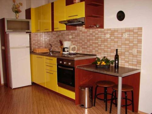 uma cozinha com armários amarelos e uma mesa com bancos em Studio Apartment in Brela with Sea View, Terrace, Air Conditioning, Wi-Fi (3524-4) em Brela