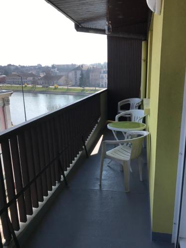 uma varanda com cadeiras e uma mesa e vista para a água em Le Villeneuve em Gray