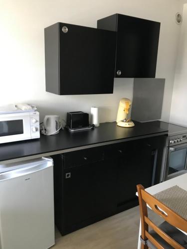 a kitchen with a black counter top and a microwave at Le Villeneuve in Gray