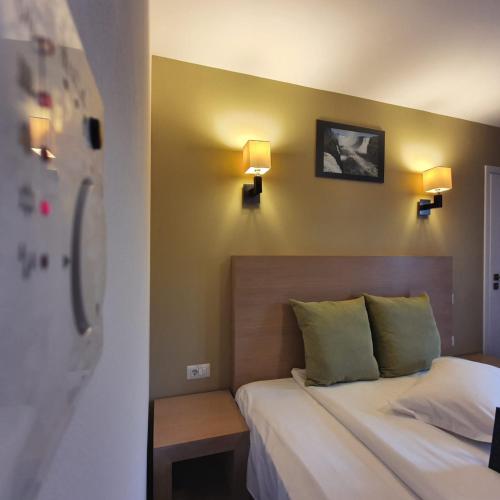 a bedroom with a bed and two lights on the wall at Hotel Escalade in Poiana Brasov