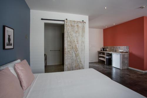 a bedroom with a white bed and a kitchen at BOHO Bohemian Boutique Hotel in Willemstad
